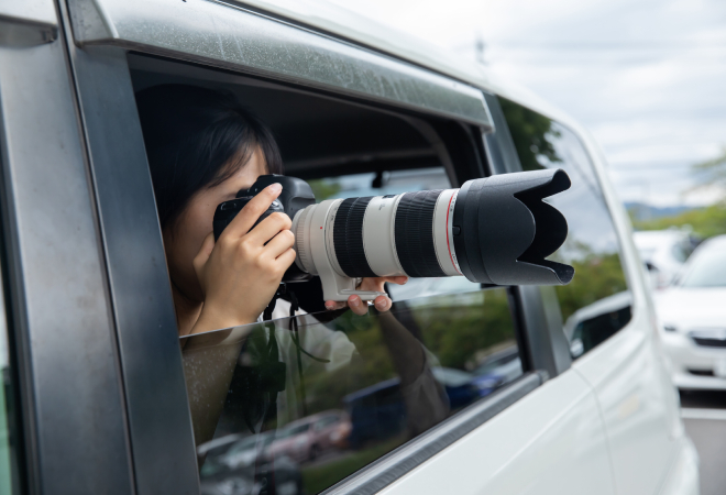 証拠写真を撮るために車内からカメラを構える女性