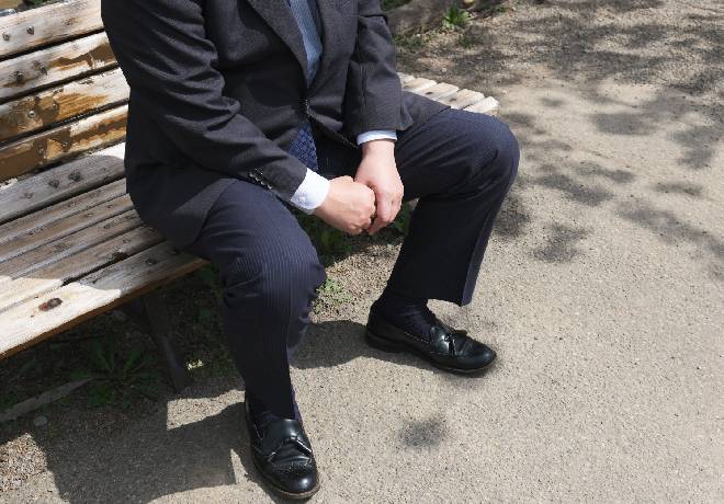 ベンチに座り込むスーツ姿の男性。
